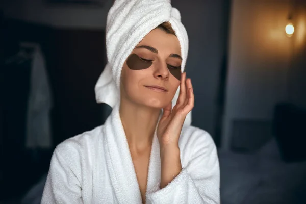 Kapalı kafa havluya banyo sonra güzel kadın portresi yamalar gözlerinin altında koyu halkalar ve kırışıklıkların koyar. Güzellik spa evde. Evde vakit bornoz çekici genç kadın 