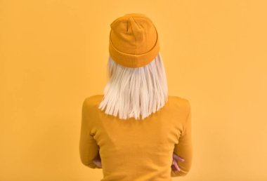 Arka görünümü tek renkli portre sarı elbise ve şapka giyen güzel sarışın kadın