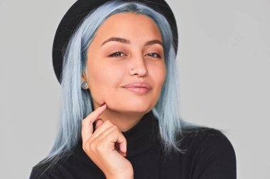 Neşeli ve sevimli genç kadının atış siyah giyim giymiş mavi saçlı kapatın ve şapka, gülümseyen. Şirin olumlu erkek ışık gri arka plan üzerinde poz. İnsanlar ve yaşam tarzı kavramı.  