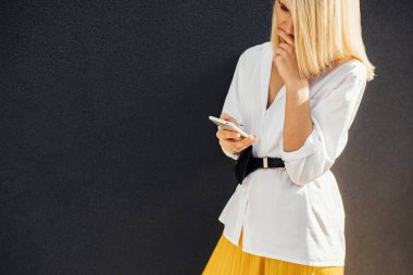 cep telefonu, açık gri duvara poz ciddi sarışın kadın manifatura