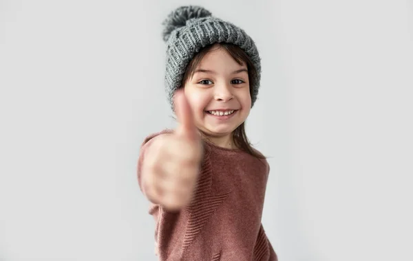 Retrato Menina Feliz Inverno Chapéu Cinza Quente Vestindo Suéter Mostrando — Fotografia de Stock