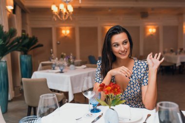 restoranda oturan ve kameraya bakarak esmer genç kadın portresi