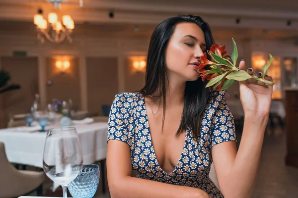 Брюнетка Молодая Женщина Сидит Ресторане Нюхает Цветы — стоковое фото
