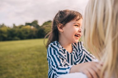 Gülüyor ve parkta güzel annesi ile oynarken mutlu sevimli küçük kız görüntüsü. Sevgi dolu anne ve kızı parkta beraber vakit. Annelik ve çocukluk. Kişi, Aile ve duygu