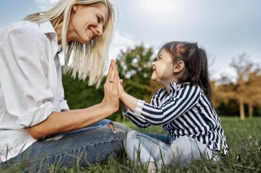 Sevimli küçük kız mutlu annesiyle dokunmadan eller eller tarafından oynarken yatay görüntü. Kadın ve onun kızı harcama zaman birlikte parkta sevgi dolu. Anne ve çocuk eğlence var. Anneler günü