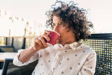 sokakta kafeterya masada kahve içme kıvırcık saçlı yakışıklı adam