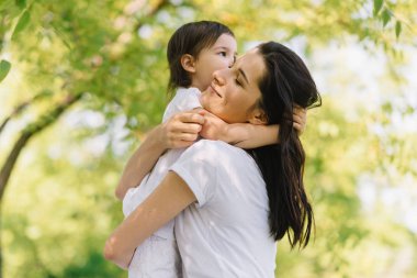 Horzintal samimi bir kadeh mutlu güzel anne ve açık havada oynarken, birbirlerine sevgi göstermek tutan şirin kızı. Anne ve onun güzel çocuk parkta oynamak. İyi ilişki içinde aile portresi.