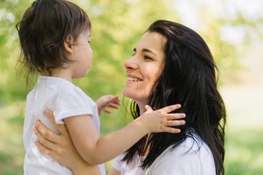 Neşeli güzel anne ve açık havada oynarken, birbirimizi tutan şirin kızı yakın çekim shot. Annem ile birlikte parkta oynayan güzel çocuğu. İyi ilişki içinde aile portresi.