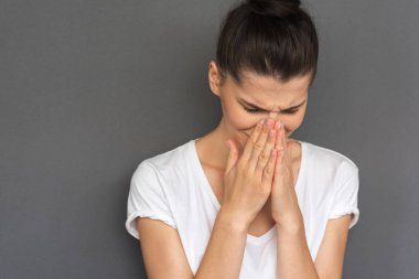 Depresif kadın portresi esmer beyaz T-shirt giyen kırpılmış, duruşmadan sonra ağlamaya gidiyor gri arka plan üzerinde izole haber dehşete. Trajik duygular, duygular üzgün, yüz ifadeleri.