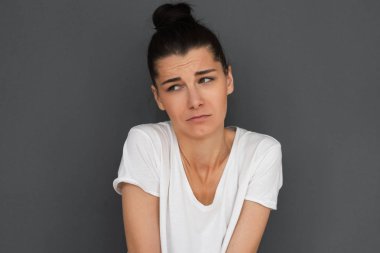 Headshot mutsuz genç esmer kadının duygu iş bir şey yanlış, bir tarafa kaşları ile seyir kaşlarını çattı için özür dilerim. Hüzünlü güzel kız duygu üzgün ve kırgın göz stüdyo gri duvar karşı.