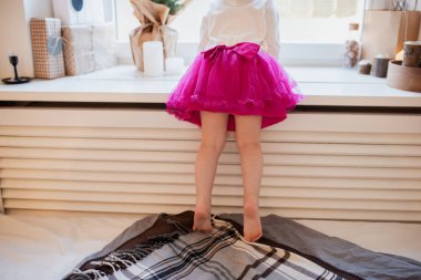 Sevimli küçük çocuk kız pencere ve wainting Noel arifesi yatağın üstünde ayakta görüntü ve arka görünümünü kırpılmış. Noel dekorasyonu. Çocuk tatil keyfini çıkarın. Mutlu Noeller ve mutlu tatiller!