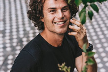 Yakışıklı genç adam açık havada cep telefonda konuşurken ayakta closeup portresi. Kameraya bakarak ve onun öğrenci arkadaşına telefon görüşmesi genç adam.