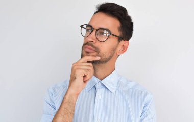 Portre resim memnun düşünceli erkek el bir yana, beyaz stüdyo özgeçmişlerine bakarak çene altında tutar. Başarılı tıraşsız adam yaratıcı proje hakkında düşünüyor mavi gömlek, kopya alanı giyer. İnsanlar
