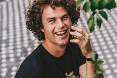 Mutlu yakışıklı genç adamın açık havada cep telefonda konuşurken ayakta portre vurdu. Öğrenci arkadaşını telefonla gülümseyen ve kamera için arayan genç adam.