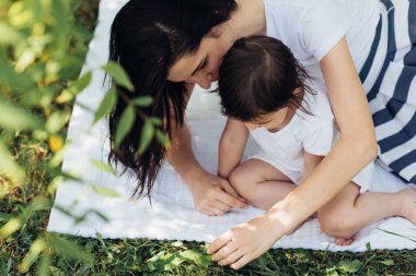 Mutlu anne ve küçük kızı açık havada oynamak güzel, yeşil çim keşfetmek. Şirin anne ve birlikte parkta oynarken onun çocuk. Mutlu aile portresi. Annelik ve çocukluk.