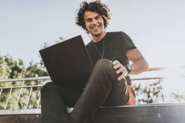 Mutlu erkek için ücretsiz kablosuz bağlı dizüstü aygıtı, arkadaşlarınızla sohbet online gülümseyerek. Neşeli erkek blogger sonrası sokakta açık bilgisayarda Web sitesinde yayımlama