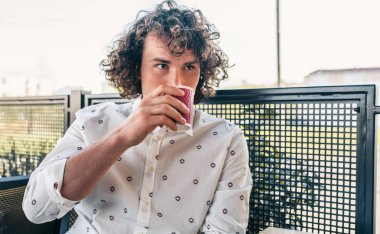 sokakta kafeterya masada kahve içme kıvırcık saçlı yakışıklı adam