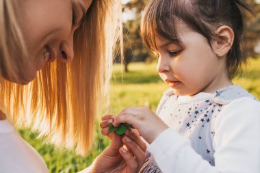 Güzel anne ve açık havada oynayan onun çocuk açık portre kadar yakın, Eko doğayı keşfetmek. Sevimli kadın ve neşeli kızı parkta oynarken. Mutlu aile portresi. Annelik ve çocukluk.