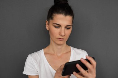 Önemli mesaj ile haber alma onun modern smartphone holding ciddi esmer işkadını samimi portresi. Genç kadın gönder kısa mesaj ile businesspartners toplantı için konsantre.