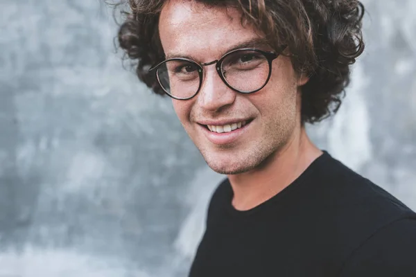 Homem Bonito Sorridente Com Cabelo Encaracolado Posando Contra Parede Cinza — Fotografia de Stock