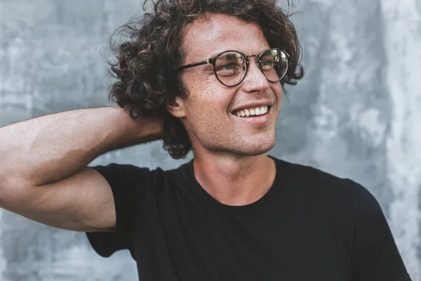 Homem Bonito Sorridente Com Cabelo Encaracolado Posando Contra Parede Cinza — Fotografia de Stock