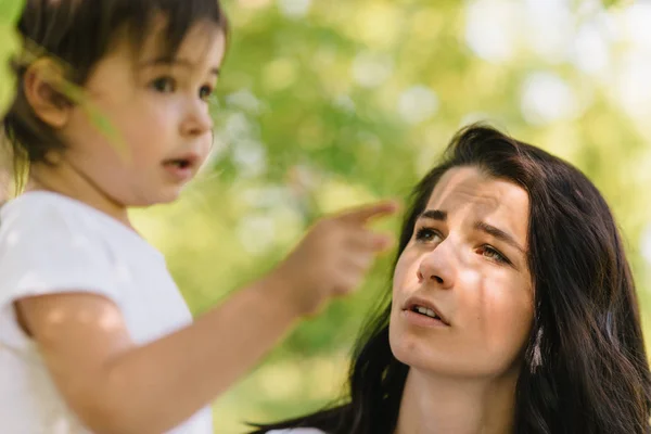 Yakın çekim yatay bir kadeh endişeli güzel anne ve gtime birlikte açık havada spendin sevimli kızı. Anne ve güzel çocuğunu parkta birlikte konuşuyor. İlişki çekmek. Annelik