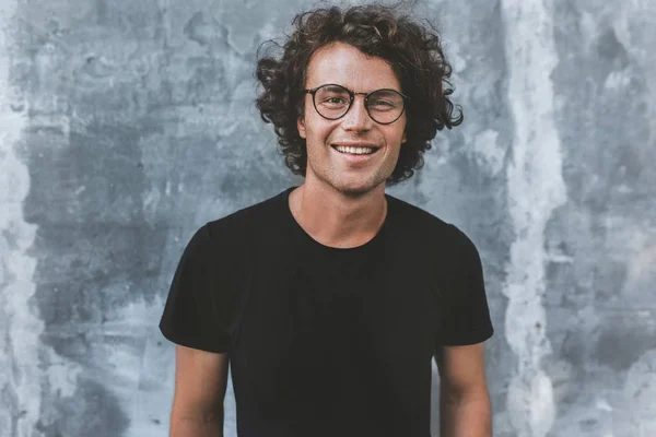 Homem Bonito Sorridente Com Cabelo Encaracolado Posando Contra Parede Cinza — Fotografia de Stock