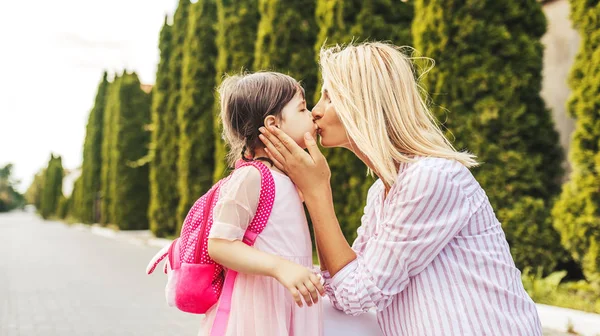 快乐可爱的小女孩和美丽的母亲拥抱和亲吻对方面前的亲属格鲁恩的水平肖像 妈妈和学龄前儿童在户外 母亲节 学校概念 — 图库照片