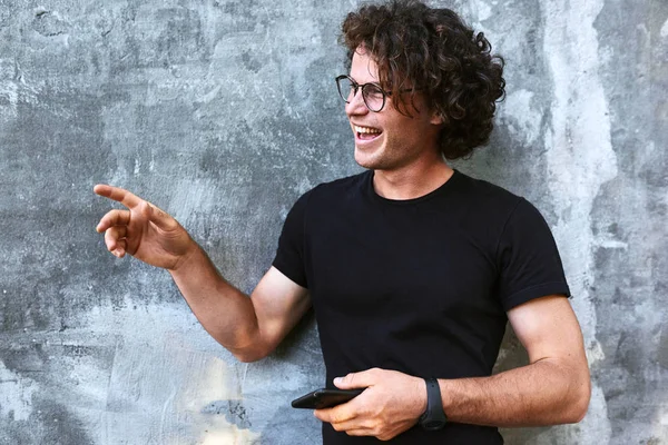 Hombre Guapo Feliz Con Pelo Rizado Sosteniendo Teléfono Móvil Mientras — Foto de Stock