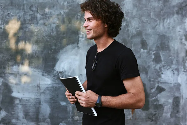 student man with curly hair holding book