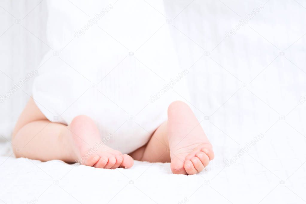 Low section of baby standing on white background. Baby foot.