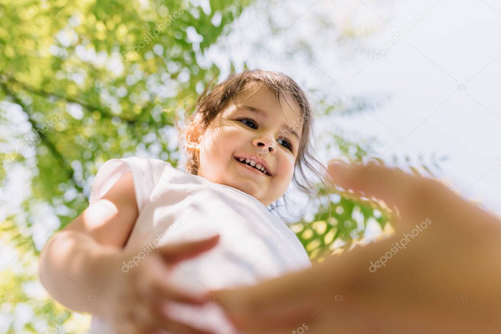 Horizontal bottom view of happy smiling little toddler cute girl kid have fun with mother outdoors in park. Good relationship of mom and child. Happy Mother's Day. Happy childhood concept. Copy space