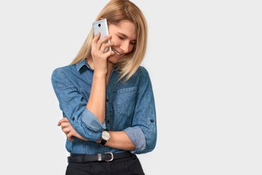 Güzel sarışın genç kadın sevgilisi, neşeli ve mutlu, beyaz stüdyo arka plan üzerinde poz arıyorsunuz için cep telefonuyla konuşuyor. Akıllı onun meslektaşı ile konuşan beyaz iş kadını