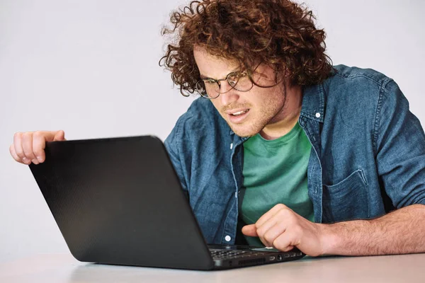 Ernstige Jonge Man Met Krullend Haar Zit Aan Zijn Bureau — Stockfoto