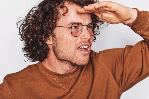 Primer plano imagen de estudio del hombre sorprendido posando para la publicidad lleva gafas redondas, mirando hacia otro lado con la mano en la frente, aislado en la pared blanca. Retrato de un estudiante inteligente. Gente concepto de emoción — Foto de Stock