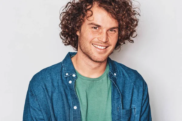 Jovem empreendedor feliz posando para propaganda na parede do estúdio branco, vestindo camisa azul, com espaço de cópia para o seu texto informativo. Conceito de pessoas e emoções — Fotografia de Stock