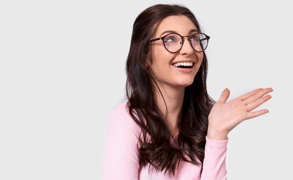 Candid studio portrait of beautiful young woman, broad smile, wears casual outfit and spectacles. Caucasian brunette female in pink blouse posing over white studio wall. People and emotion concept — Stock Photo, Image