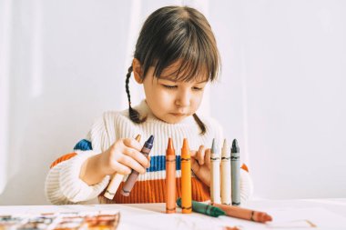 Petrol kalemler, evde beyaz masa başında oturan ile oynarken, yaratıcı, sevimli küçük kız portresi. Çok okul öncesi çocuk ile kalemler çizer. Kişi, çocukluk ve eğitim kavramı