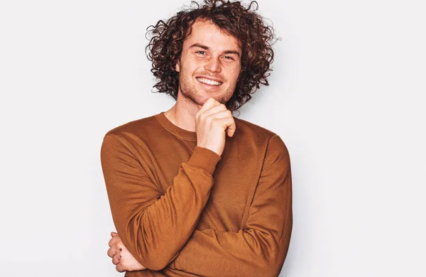 Image of Caucasian male with curly hair smiling and posing for advertisement wears brown pullover, isolated on white wall with copy space for your promotion text. People, emotion and lifestyle concept — Stock Photo, Image