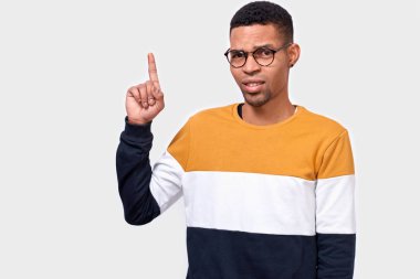 Akıllı genç adam gösterir ile ön plana boş kopya alanı, giyer renkli kazak, parmak pozitif gülümseme vardır. Reklam ve etnisite kavramı