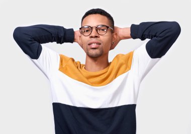 Kapalı renkli süveter ve beyaz arka plan üzerinde poz yuvarlak trendy gözlük başının arkasında stüdyo portre ile gülümseyen genç bir adamın eller