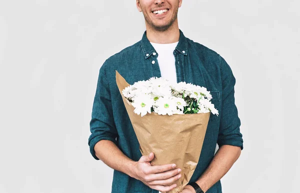 Молодой счастливый человек улыбается и доставляет букет белых цветов. обрезанный снимок красивого мужчины с кучей цветов, готовящихся к свиданию с девушкой. День Святого Валентина. Концепция Дня матери — стоковое фото