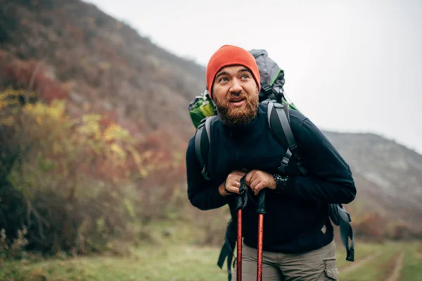 英俊的白种人年轻男子带着旅行背包在山上徒步的户外拍摄。旅行者留胡子的男性在假期徒步后休息一下。旅行、人和生活方式概念 — 图库照片