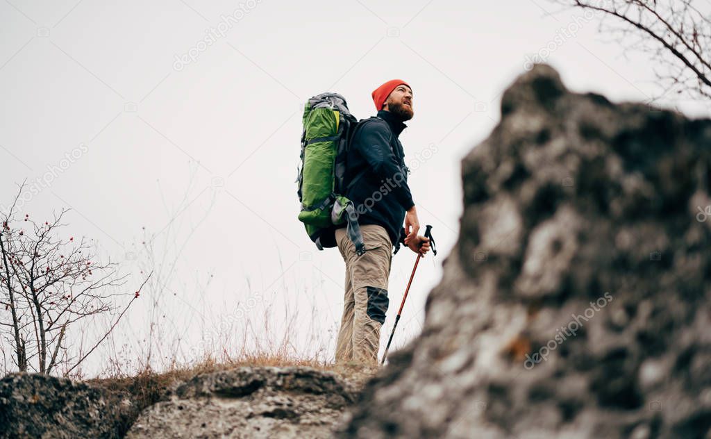Landscape shot of traveler bearded man trekking and mountaineering during his journey. Tourist young male hiking in mountains, finished his track. Travel, people, sport and healthy lifestyle concept