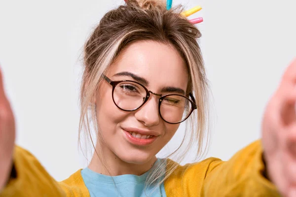 Close up studio shot di allegra giovane donna con bella pelle pulita, indossa occhiali trasparenti, facendo selfie su sfondo bianco . — Foto Stock