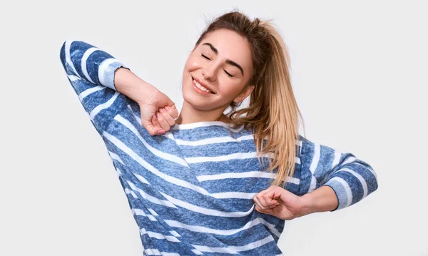 Horizontal studio portrait of pleased young European woman closes eyes and smiles gently, wakes up in good mood, dressed in casual home clothes. People positive emotions concept — Stock Photo, Image