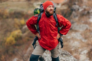 Yatay açık havada atış kırmızı elbiseler giymiş dağlar'da genç erkek yürüyüş uzakta görünüyor. Gezgin sakallı adam yaptığı yolculuk sırasında trekking sonra rahatlatıcı. Seyahat, insanlar, spor ve yaşam tarzı kavramı