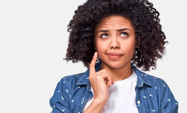 Close up shot of uncertain African American woman has puzzled expression, frowns her face and looking up. Mulher de pele escura duvidosa não pode fazer escolha, questionou a expressão, isolado no branco . — Fotografia de Stock