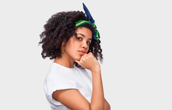 Estudio aislado primer plano retrato de mujer joven con estilo con el pelo peludo oscuro tocando su barbilla y mirando a la cámara con expresión escéptica. Mujer afroamericana tiene expresión reflexiva . — Foto de Stock