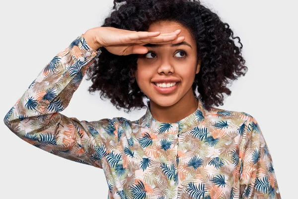 Primer plano retrato de estudio de la hermosa joven afroamericana mirando hacia otro lado con la mano en la frente, sonriendo ampliamente, de pie sobre fondo blanco. Gente concepto de emociones positivas — Foto de Stock